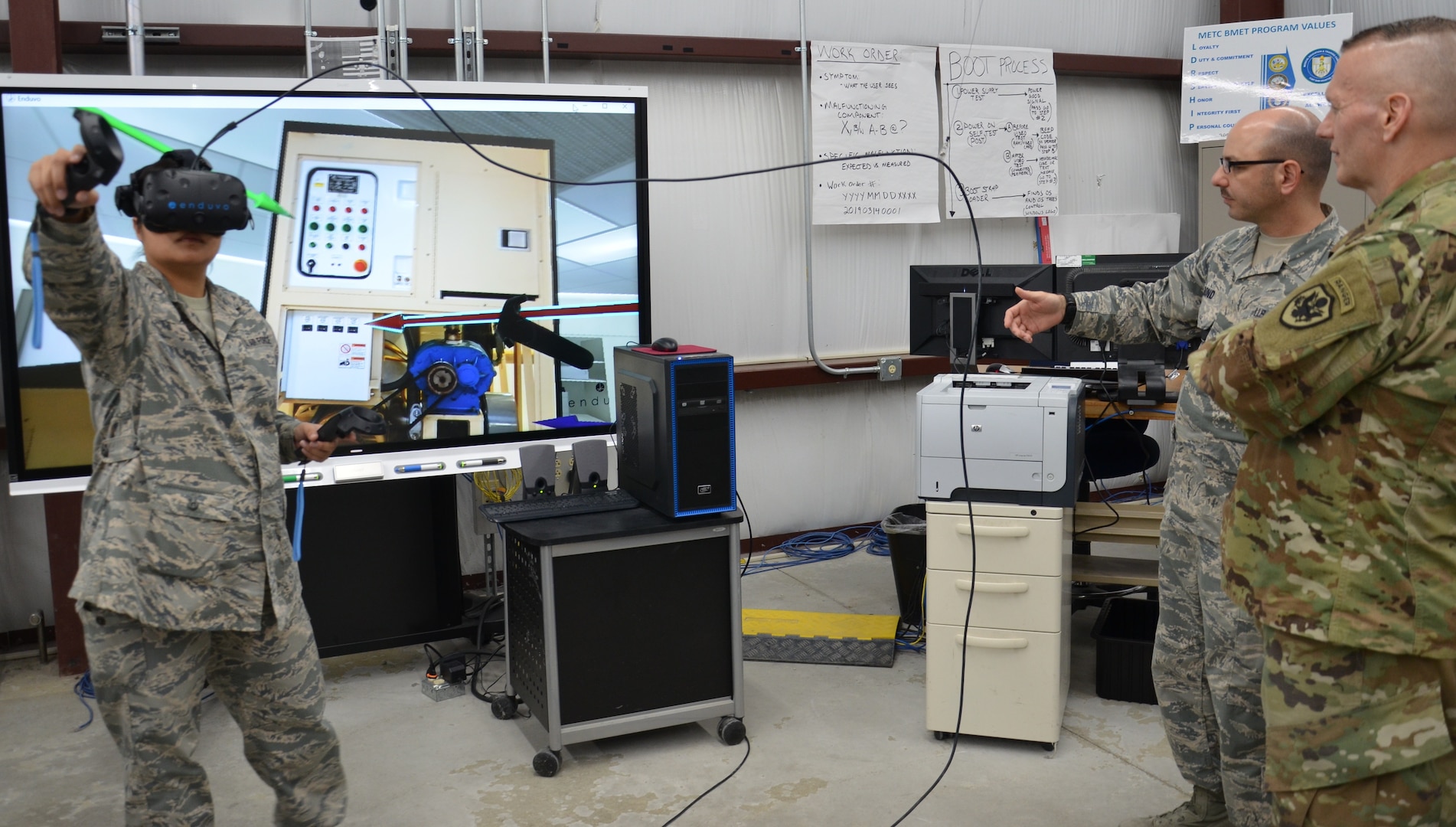 Command Sgt. Major John Wayne Troxell, senior enlisted advisor to the Chairman of the Joint Chiefs of Staff and the senior non-commissioned officer in the U.S. Armed Forces, observes as Staff Sgt. Jemima Alvarez, an instructor in the Biomedical Equipment Technician program, demonstrates a virtual interactive classroom modality that the program is testing as a training tool for repairing Expeditionary Deployable Oxygen Concentration System units while BMET instructor Master Sgt. Christian Bond explains how it works.