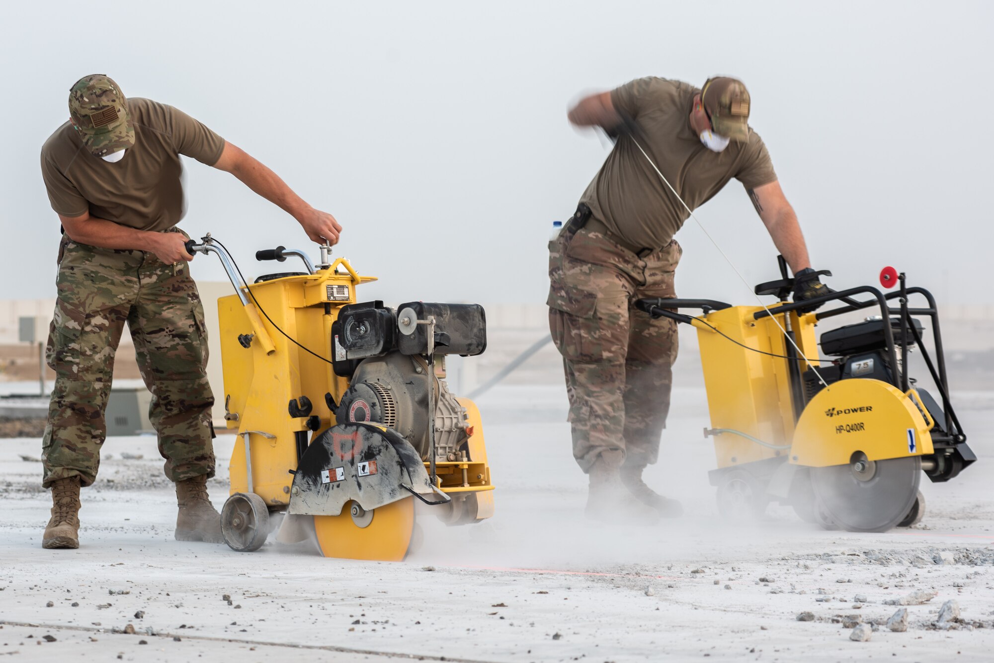 Two 380th Expeditionary Civil Engineer Squadron water and fuels technicians cut concrete during a rapid airfield damage repair exercise July 26, 2019, at Al Dhafra Air Base, United Arab Emirates. By cutting the concrete it can be broken up and removed efficiently, leaving the hole to be filled with fast-curing concrete. (U.S. Air Force photo by Staff Sgt. Chris Thornbury)