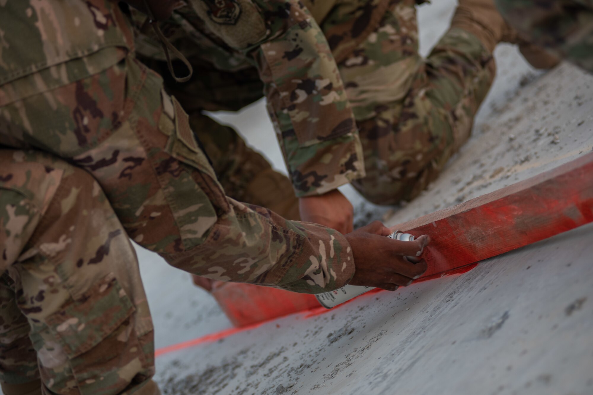 Three 380th Expeditionary Civil Engineer Squadron water and fuels technicians mark damaged areas during a rapid airfield damage repair exercise July 26, 2019, at Al Dhafra Air Base, United Arab Emirates. The damaged areas are broken up and removed, then replaced with fast-curing concrete to get the airfield operational quickly and efficiently. (U.S. Air Force photo by Staff Sgt. Chris Thornbury)