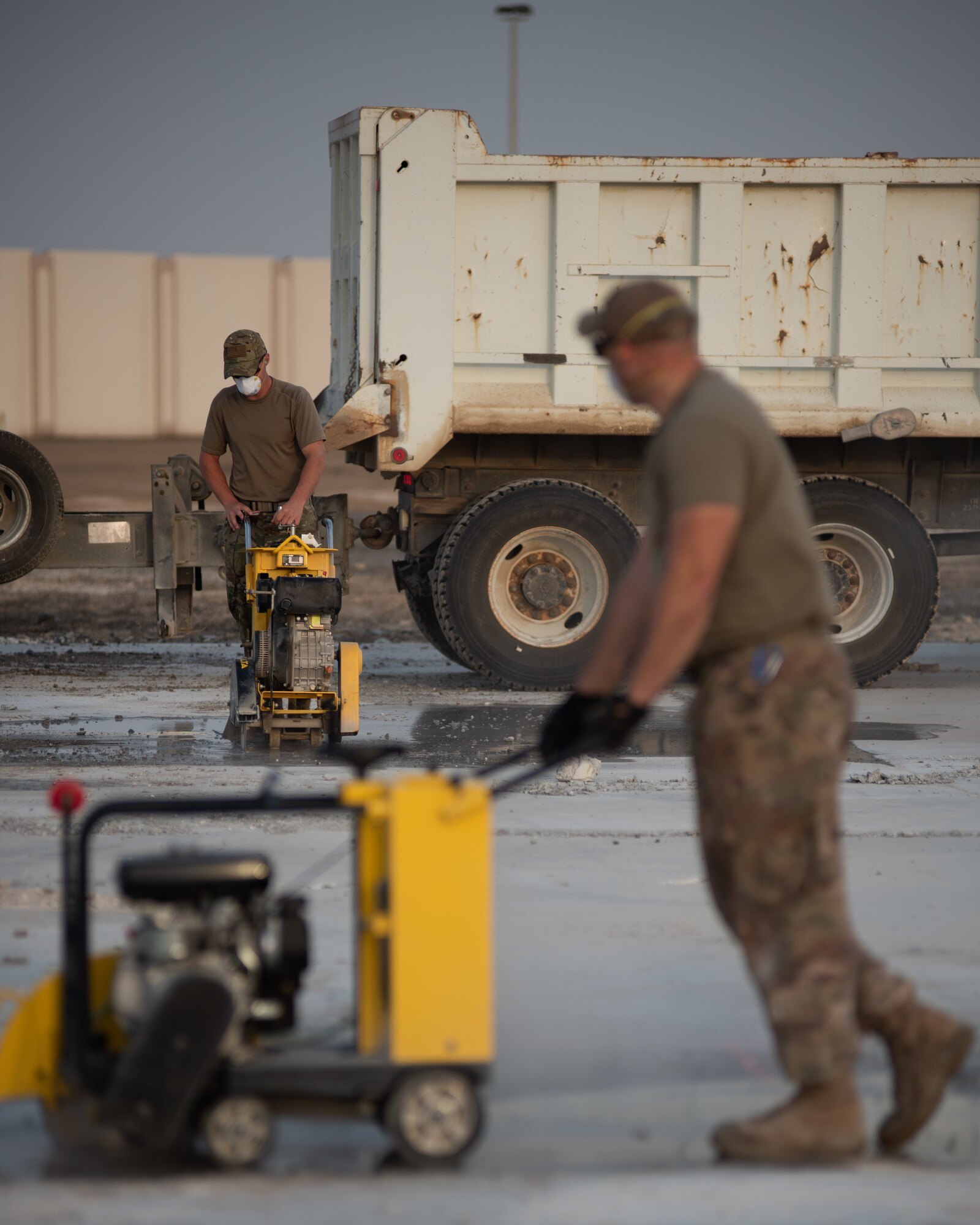 Two 380th Expeditionary Civil Engineer Squadron water and fuels technicians cut concrete during a rapid airfield damage repair exercise July 26, 2019, at Al Dhafra Air Base, United Arab Emirates. By cutting the concrete it can be broken up and removed to be filled with fast-curing concrete. (U.S. Air Force photo by Staff Sgt. Chris Thornbury)