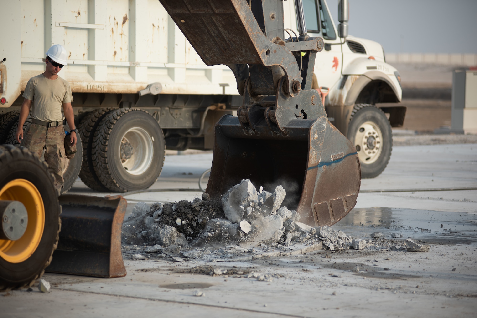 An excavator collects and lifts concrete during a rapid airfield damage repair exercise July 26, 2019, at Al Dhafra Air Base, United Arab Emirates. Removing the concrete allows the team to replace the damaged area with new fast-curing concrete to get the airfield operational within hours. (U.S. Air Force photo by Staff Sgt. Chris Thornbury)