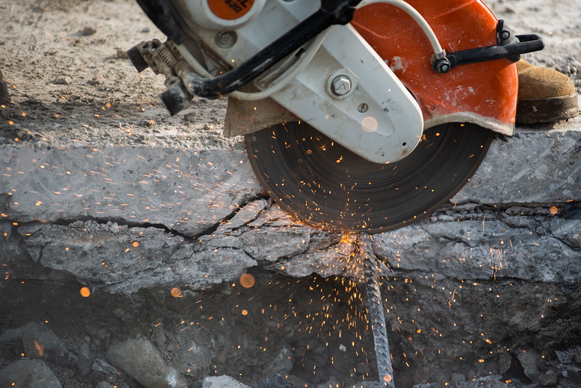 A 380th Expeditionary Civil Engineer Squadron Dirt Boy cuts rebar with a cut-off machine during a rapid airfield damage repair exercise July 26, 2019, at Al Dhafra Air Base, United Arab Emirates. The rebar is cut to create more room for an excavator to remove damaged concrete. (U.S. Air Force photo by Staff Sgt. Chris Thornbury)