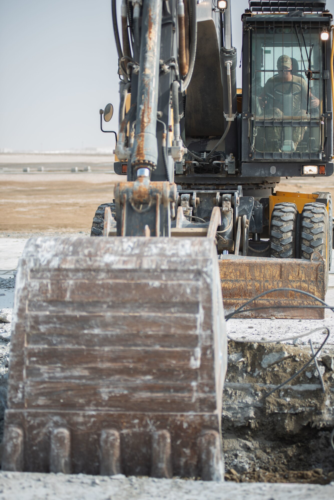 Senior Airman David Smith, 380th Expeditionary Civil Engineer Squadron heavy machine operator, operates an excavator to collect and lift concrete during a rapid airfield damage repair exercise July 26, 2019, at Al Dhafra Air Base, United Arab Emirates. Removing the concrete allows the team to replace the damaged area with new fast-curing concrete to get the airfield operational within hours. (U.S. Air Force photo by Staff Sgt. Chris Thornbury)