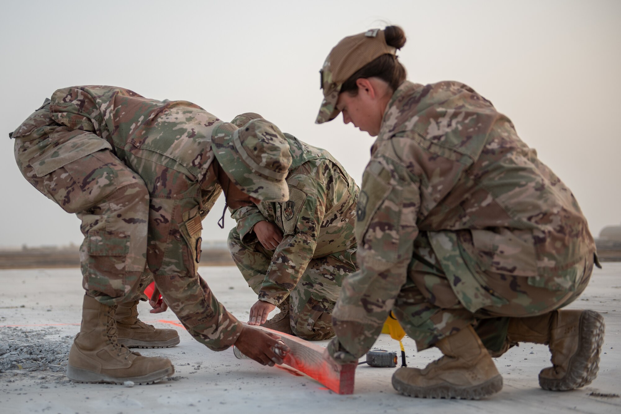 Two 380th Expeditionary Civil Engineer Squadron water and fuels technicians mark lines on concrete during a rapid airfield damage repair exercise July 26, 2019, at Al Dhafra Air Base, United Arab Emirates. By removing damaged areas of concrete it can be replaced with fast-curing concrete to get the airfield operational quickly and efficiently. (U.S. Air Force photo by Staff Sgt. Chris Thornbury)