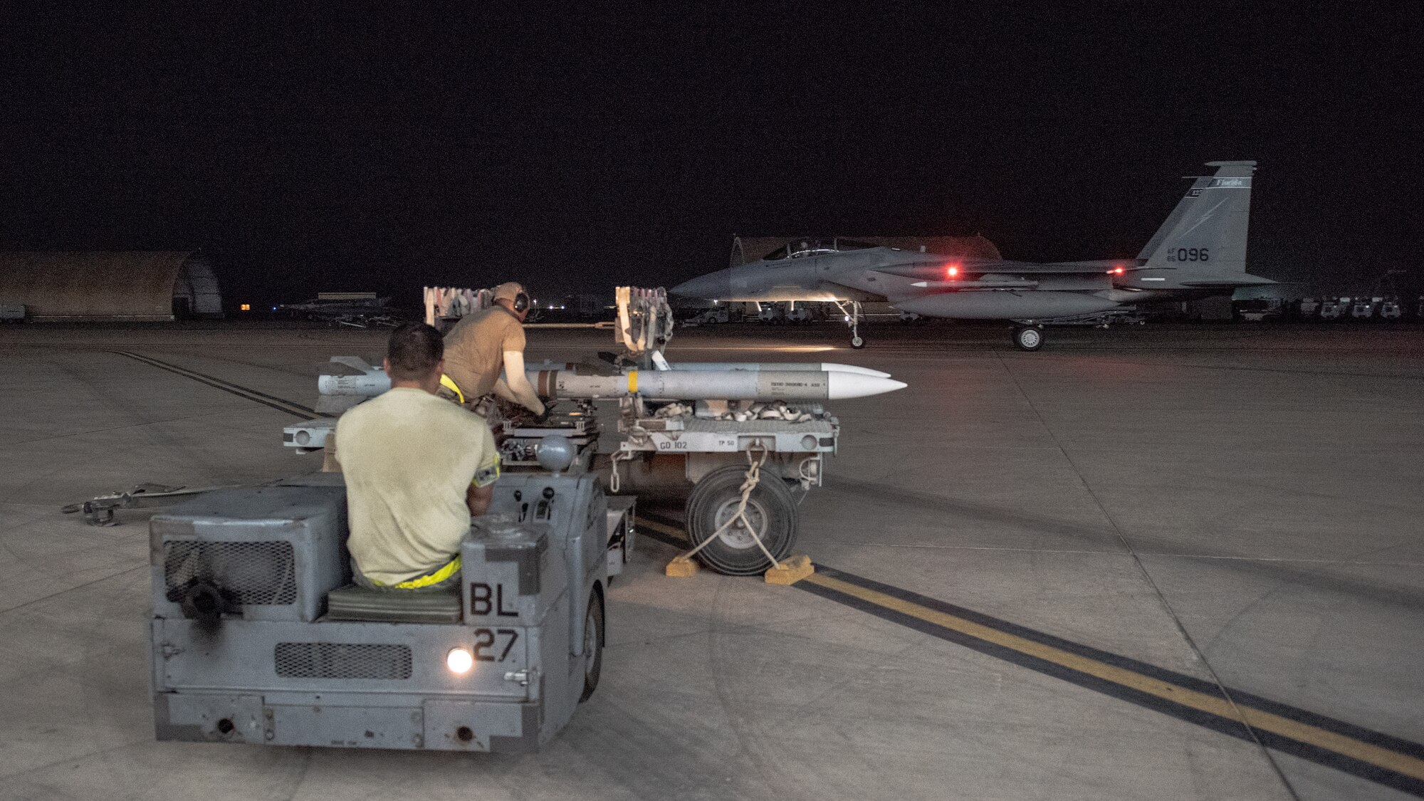 An F-15E Strike Eagle weapons load crew team prepares to lift an AIM-120D to attach to a pylon July 15, 2019, at Al Dhafra Air Base, United Arab Emirates. The AIM-120D is the latest Advanced Medium-Range Air-to-Air missile (AMRAAM) and features improved navigation, kinematics, lethality and hardware and software updates to enhance its electronic protection capabilities against more capable threats. (U.S. Air Force photo by Staff Sgt. Chris Thornbury)