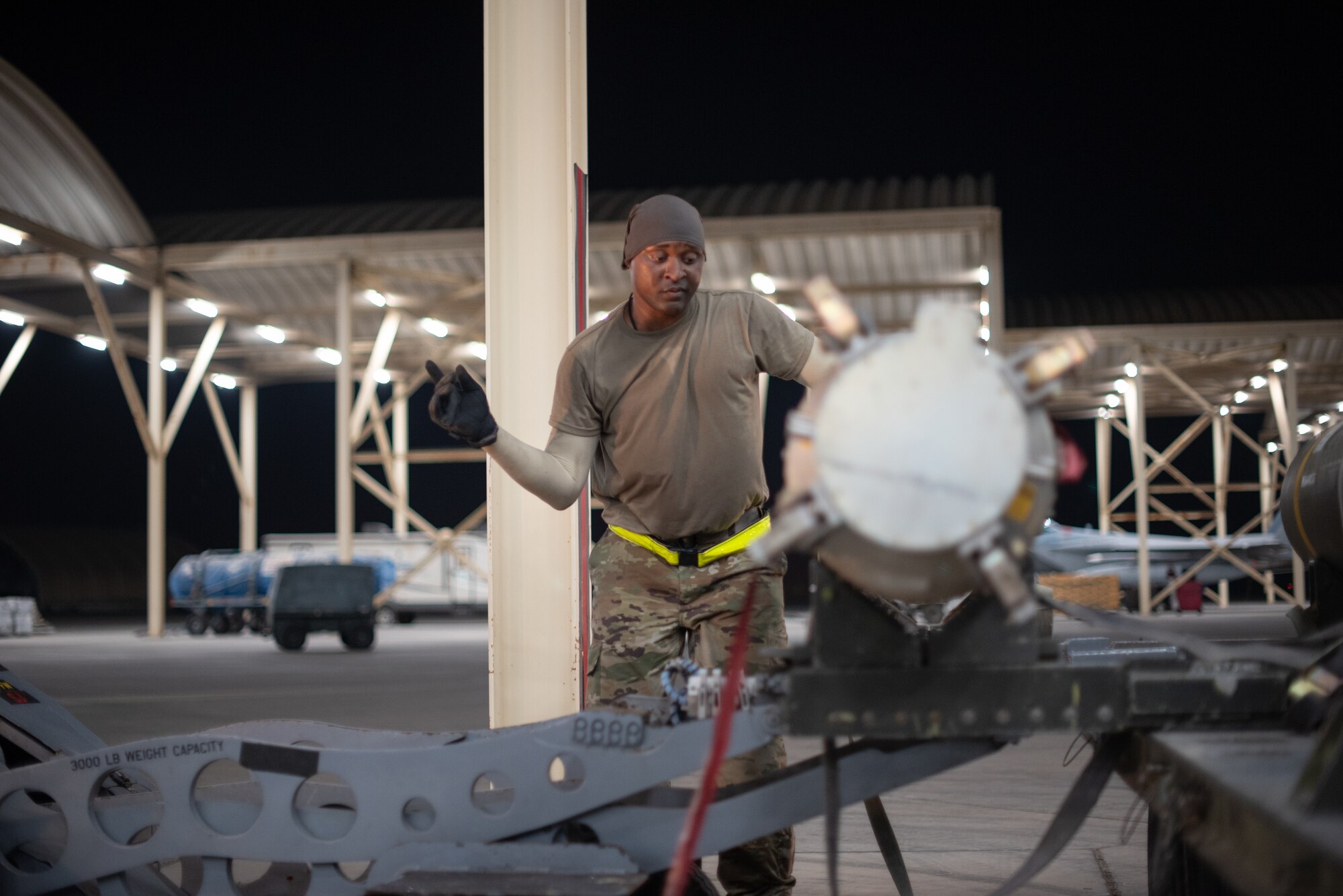 Staff Sgt. Kiefer May, 380th Expeditionary Aircraft Maintenance Squadron weapons load crew team chief, guides the lift operator July 15, 2019, at Al Dhafra Air Base, United Arab Emirates. Weapons load crews work 24/7 operations to support loading and configuring various munitions for the F-35A Lightning II, F-15E Strike Eagle and F-15C Eagle jets at ADAB. (U.S. Air Force photo by Staff Sgt. Chris Thornbury)