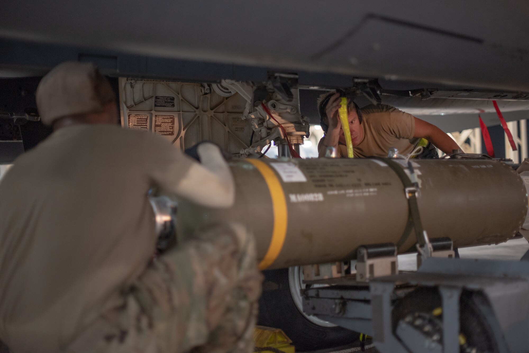 Senior Airman Sean Logan, 380th Expeditionary Aircraft Maintenance Squadron weapons load crew team member, guides the lift operator to attach a munition July 15, 2019, at Al Dhafra Air Base, United Arab Emirates. The F-15E is a dual-role fighter designed to perform air-to-air and air-to-ground missions and is currently supporting surface combat air patrol operations in the Arabian Gulf. (U.S. Air Force photo by Staff Sgt. Chris Thornbury)