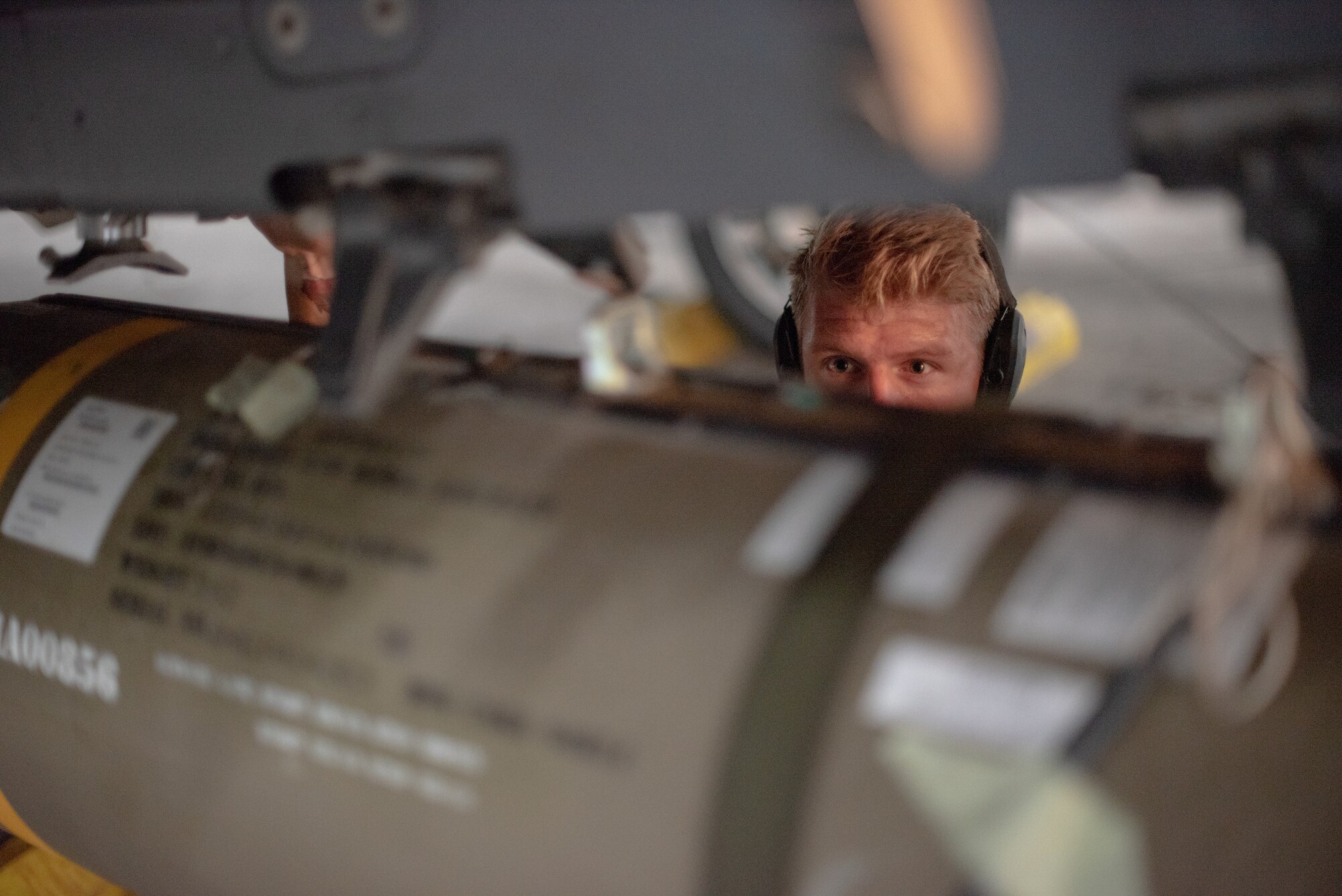 Senior Airman Sean Logan, 380th Expeditionary Aircraft Maintenance Squadron weapons load crew team member, watches a munition rise to an F-15E Strike Eagle pylon July 15, 2019, at Al Dhafra Air Base, United Arab Emirates. Diverse weapons loads on the F-15E arm the jet with a multitude of capabilities while flying in support of maritime combat air patrol missions in the Arabian Gulf. (U.S. Air Force photo by Staff Sgt. Chris Thornbury)