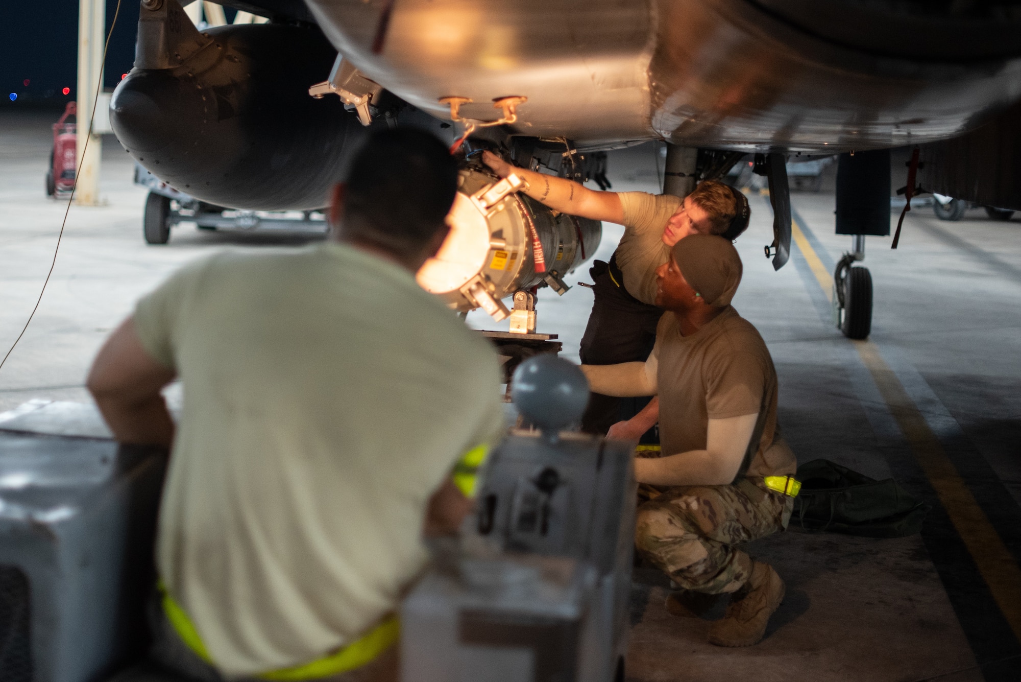 An F-15E Strike Eagle weapons load crew team attaches a munition to a pylon July 15, 2019, at Al Dhafra Air Base, United Arab Emirates. Diverse weapons loads on the F-15E arm the jet with a multitude of capabilities while flying in support of maritime combat air patrol missions in the Arabian Gulf. (U.S. Air Force photo by Staff Sgt. Chris Thornbury)