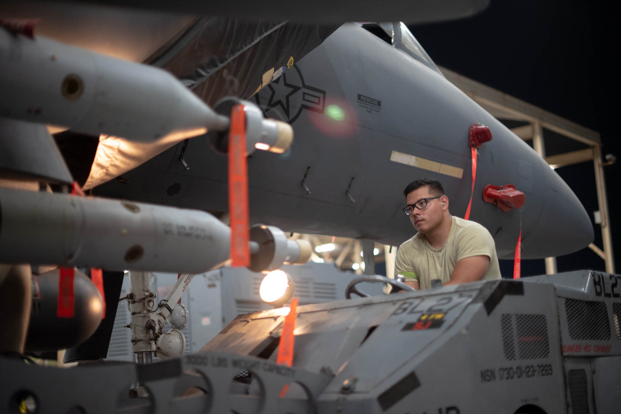 Airman 1st Class Jose Lopez, 380th Expeditionary Aircraft Maintenance Squadron weapons load crew team member, drives a GBU-12 under an F-15E Strike Eagle July 15, 2019, at Al Dhafra Air Base, United Arab Emirates. The F-15E has the capability to carry any air-to-surface weapon in the Air Force inventory. (U.S. Air Force photo by Staff Sgt. Chris Thornbury)