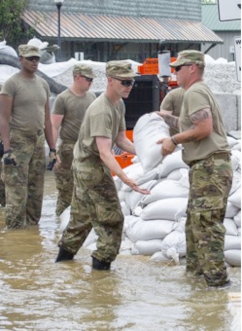 Soldiers from Battery B, 2nd Battalion, 123rd Field Artillery place sandbags shoring up concrete barriers in Grafton, Illinois, during flood operations in June.