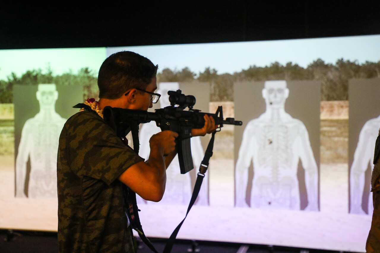 A teen points a rifle at a simulated gun range target.