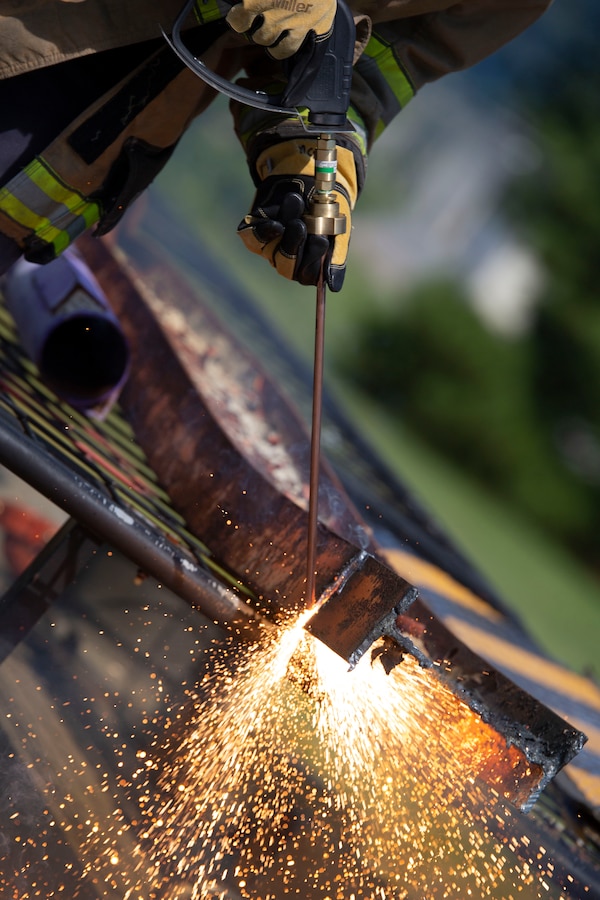 A firefighter from Marine Corps Air Station Beaufort Fire and Emergency Services cuts an iron plate using a burning rod of metal aboard Marine Corps Air Station Beaufort, July 25. This was taught to the first responders in order to combat full mechanical entrapment of a person. (U.S. Marine Corps photo by Lance Cpl. Aidan Parker)