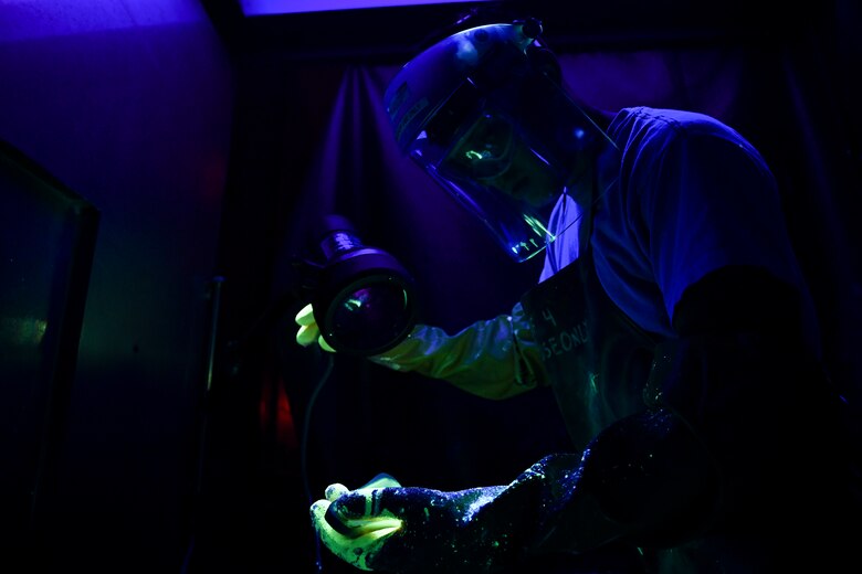 Specialist performs a fluorescent-penetrant inspection on an aircraft part