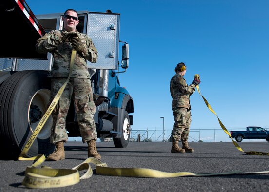 U.S. Air Force Senior Airmen Ben Hetzel and Ashley Pruitt, 92nd Logistics Readiness Squadron ground transportation journeymen, recoil cargo ratchet straps after unloading pallets of material during a Cargo Deployment Function exercise at Fairchild Air Force Base, Washington, July 24, 2019. Team Fairchild LRS Airmen practice quick cargo deployment often to execute air mobility support. (U.S. Air Force photo by Airman 1st Class Whitney Laine)
