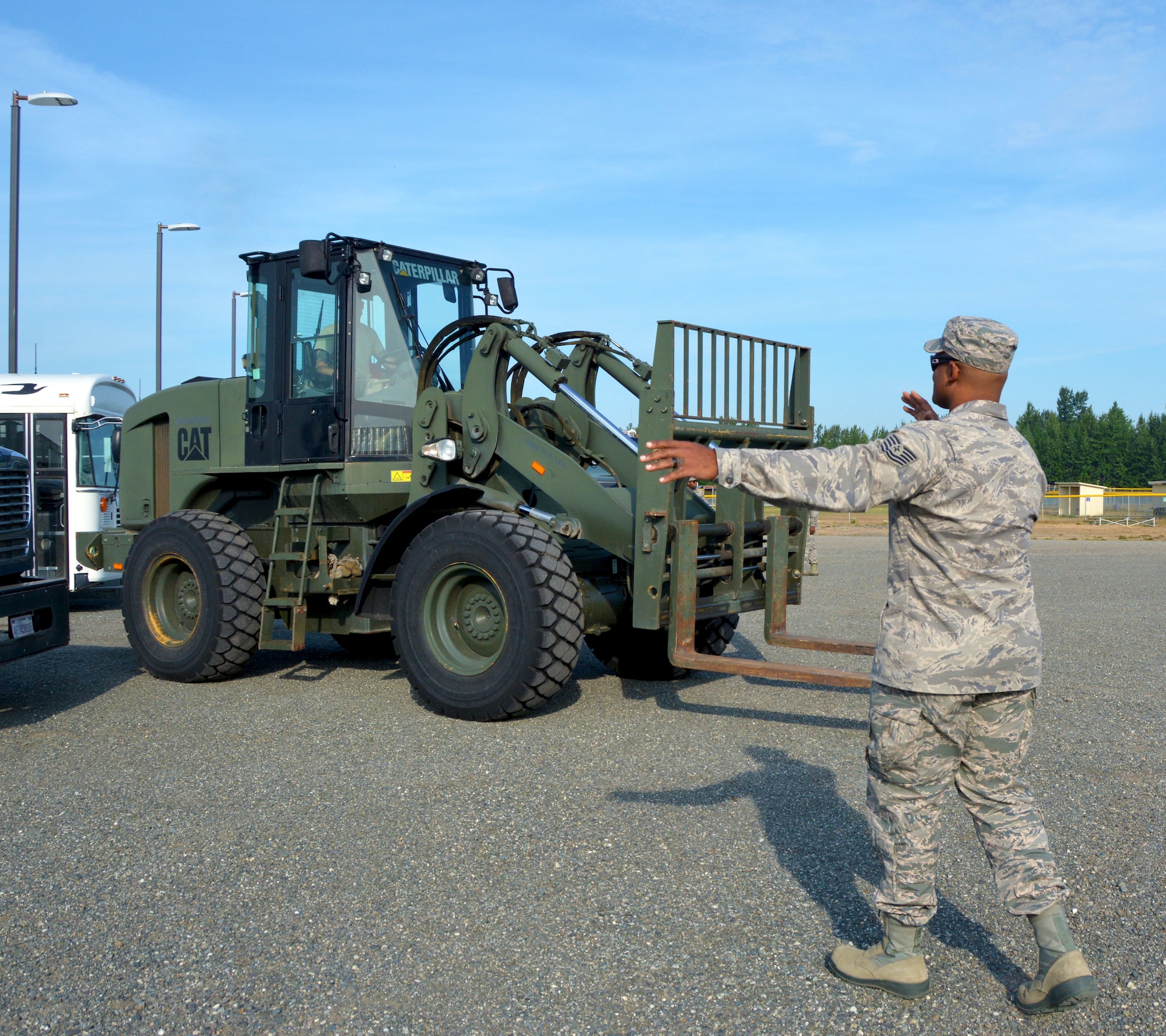 Tech. Sgt. Terry Cooper, 507th Logistics Readiness Squadron ground transportation quality assurance, guides the driver of an all-terrain forklift July 18, 2019, at Joint Base Elmendorf-Richardson, Alaska. (U.S. Air Force photo by Tech. Sgt. Samantha Mathison)