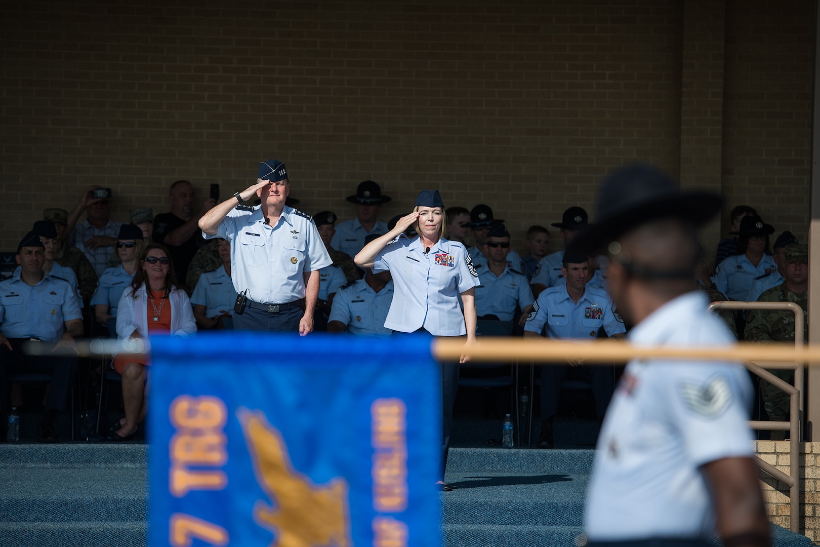 U.S. Air Force Lt. Gen. Brad Webb (right), commander of Air Education and Training Command (AETC), and Chief Master Sgt. Julie Gudgel, AETC command chief, salute basic military trainees during the graduation parade Aug. 2, 2019, at Joint Base San Antonio-Lackland, Texas