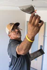 A Member of the 502nd Civil Engineering Group spreads joint compound on the ceiling of a dorm room impacted by mold August 1, 2019, at Joint Base San Antonio-Lackland, Texas. After an assessment, remediation steps include ensuring heating, ventilation and air conditions systems are properly working, as well as installing dehumidifiers, exhaust and ceiling fans. In order to reduce mold and humidity challenges, carpeting is being replaced with vinyl planking.