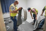 Members of the 502nd Civil Engineering Group remove carpet from a dorm room impacted by mold August 1, 2019, at Joint Base San Antonio-Lackland, Texas. After an assessment, remediation steps include ensuring heating, ventilation and air conditions systems are properly working, as well as installing dehumidifiers, exhaust and ceiling fans. In order to reduce mold and humidity challenges, carpeting is being replaced with vinyl planking. (U.S. Air Force photo by Sean M. Worrell)