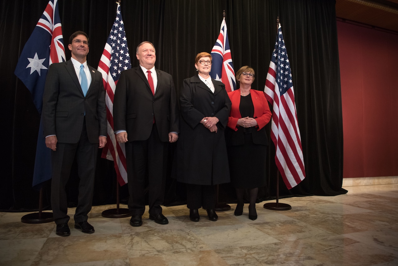 Four people in a line before U.S. and Australian flags