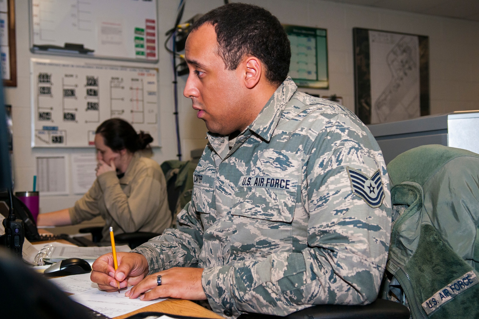 Airman taking notes on a desk with classroom in the background