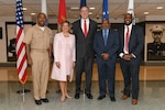 Group of five people standing in front of flags.