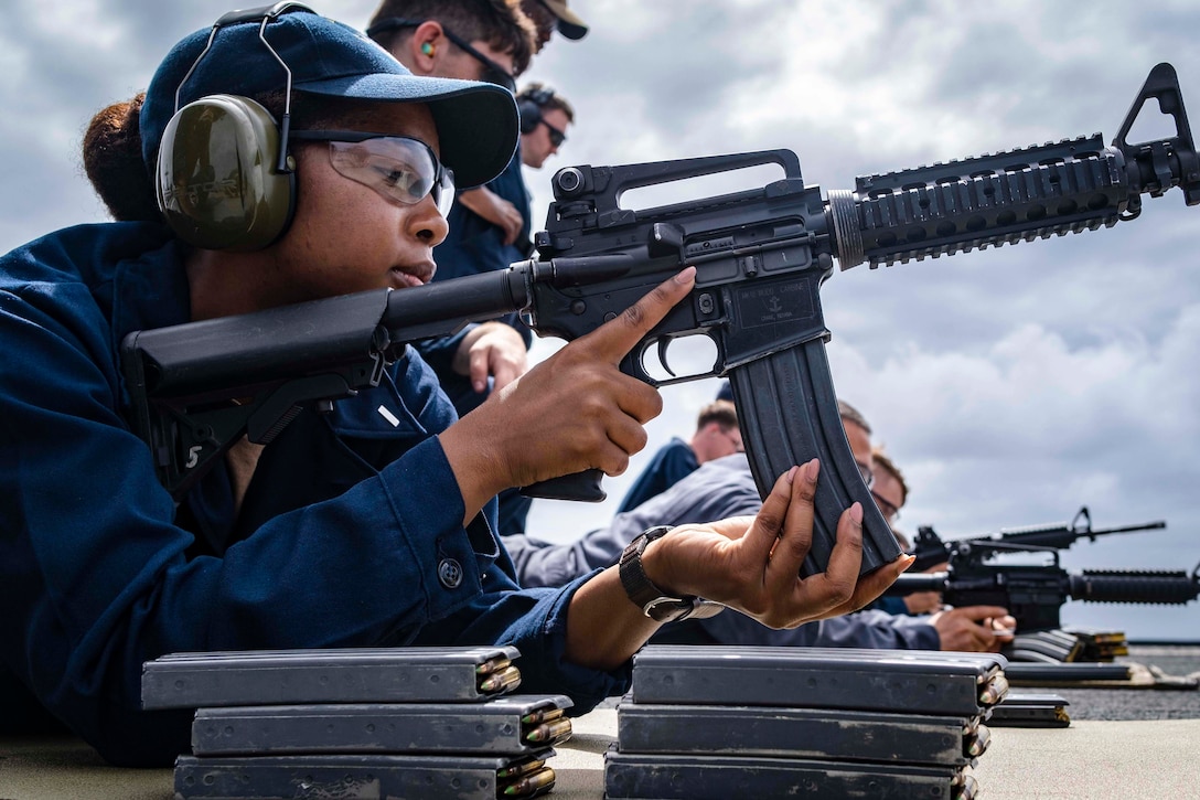 A sailor loads a magazine into a rifle.