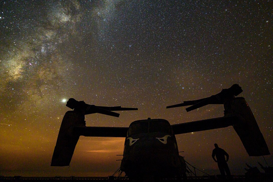 A parked aircraft with a person standing next to it at night.