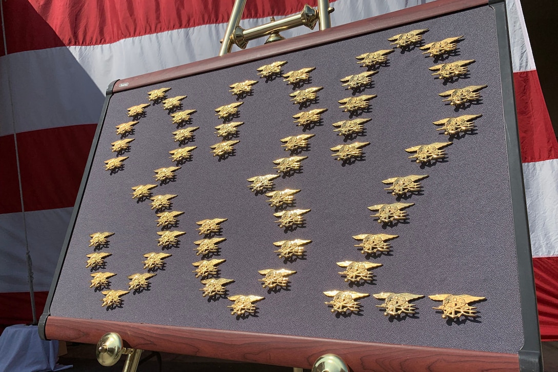 Gold pins form the number 332 on a framed display.