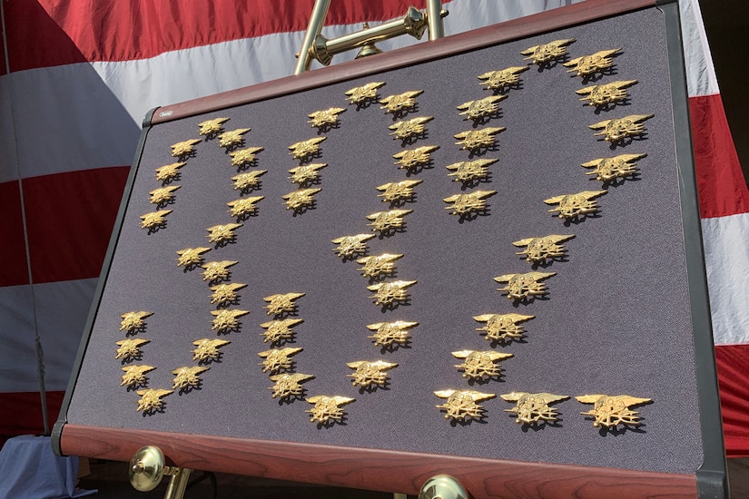 Gold pins form the number 332 on a framed display.
