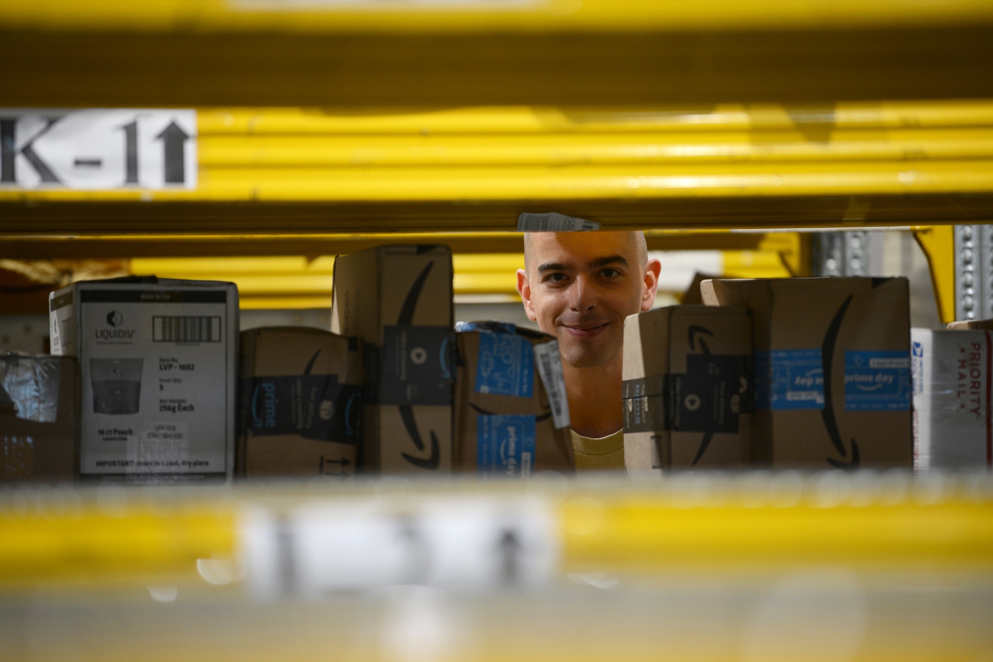 Airman 1st Class Dylan Cooper, a military postal clerk from the 31st Force Support Squadron, poses for a picture as he places a package on a shelf, Aug. 2, 2019, at Aviano Air Base, Italy. Cooper scanned and labeled various packages from an early morning shipment. (U.S. Air Force photo by Airman 1st Class Ericka A. Woolever)