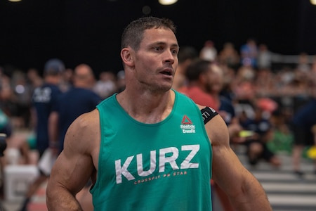 Lt. Col. Anthony Kurz, a member of the U.S. Army Warrior Fitness Team assigned to the Asymmetric Warfare Group in Fort Meade, Md., competes in the Men's Masters (40-44) Division at the 2019 CrossFit Games in Madison, Wis., Aug. 3, 2019. During the sandbag triplet event, athletes started with a 90-foot handstand walk, then moved to the air bike to burn 35 calories. They then had to carry a 200-pound sandbag for 90 feet to the finish line. (Photo Credit: Devon L. Suits)