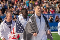 Lt. Col. Anthony Kurz and Capt. Chandler Smith, representing the U.S. Army Warrior Fitness Team, march onto the field during the 2019 CrossFit Games opening ceremony in Madison, Wis., Aug. 1, 2019. Kurz proudly displayed his U.S. Army Special Forces flag as a nod to the Special Forces community. (Photo Credit: Sgt. 1st Class Robert Dodge)