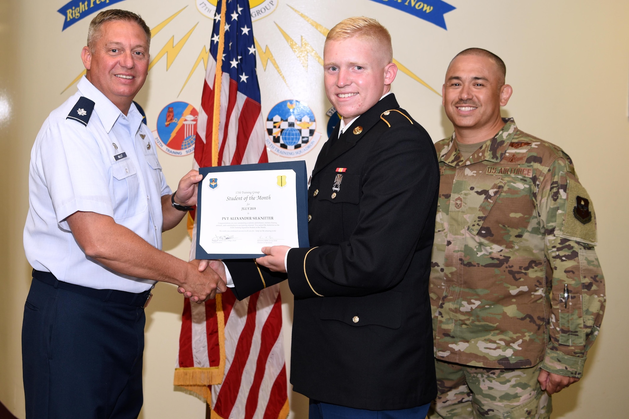 U.S. Air Force Lt. Col. Herbert Millet III, 313th Training Squadron commander, presents the 312th Training Squadron Student of the Month award to U.S. Army Pvt Alexander Silknitter, 312th TRS student, at the Brandenburg Hall on Goodfellow Air Force Base, Texas, August 2, 2019. The 312th TRS’s mission is to provide Department of Defense and international customers with mission ready fire protection and special instruments graduates and provides mission support for the Air Force Technical Applications Center. (U.S. Air Force photo by Airman 1st Class Abbey Rieves/Released)