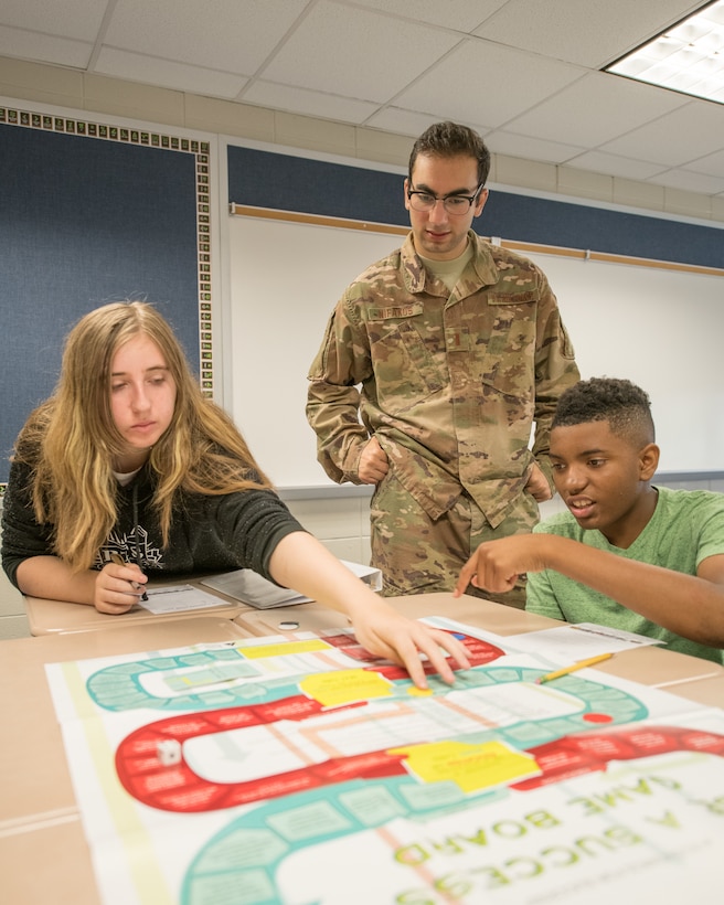 2nd Lt. George Nifakos, 436th Comptroller Squadron deputy budget officer, assists two Caesar Rodney High School freshmen with the Be a Success board game by Junior Achievement USA June 31, 2019, at Caesar Rodney High School in Camden, Del. The game teaches players about plotting career paths, pursuing education, entering the workforce and, ultimately, reaching their financial goals. (U.S. Air Force photo by Mauricio Campino)
