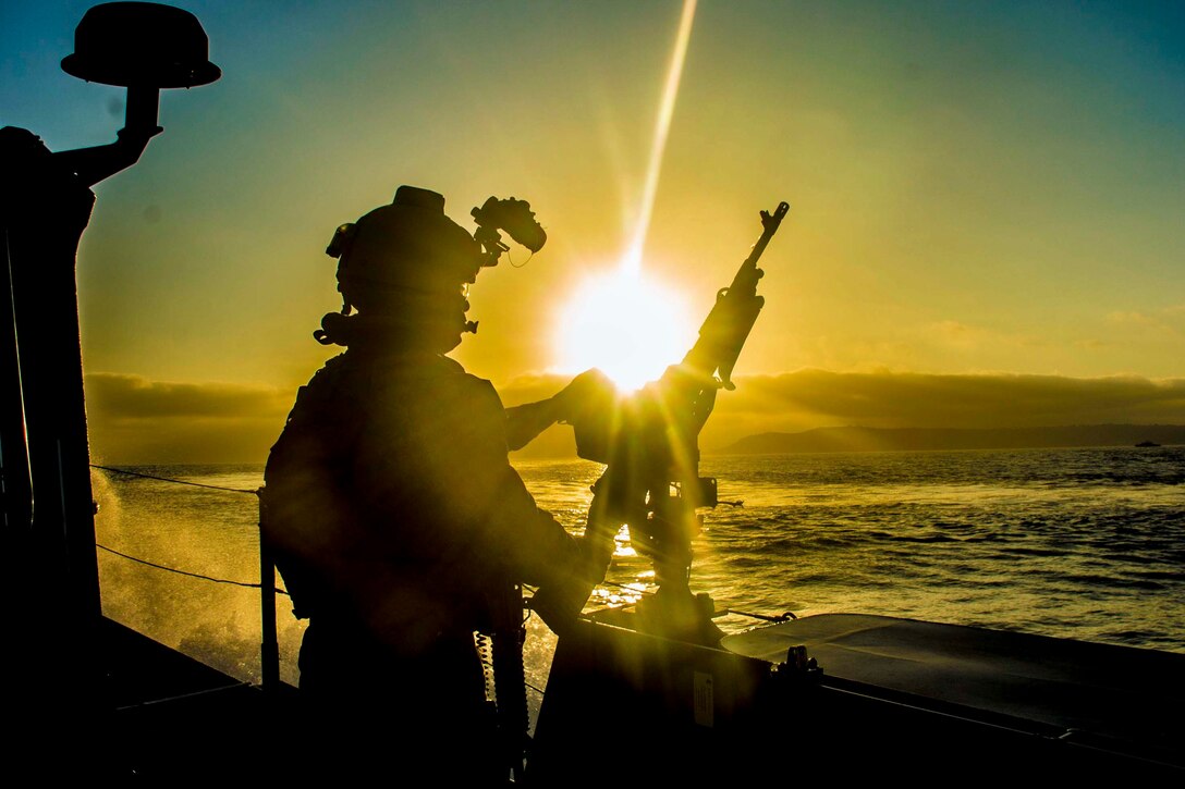 A sailor stands aboard a ship holding a weapon.