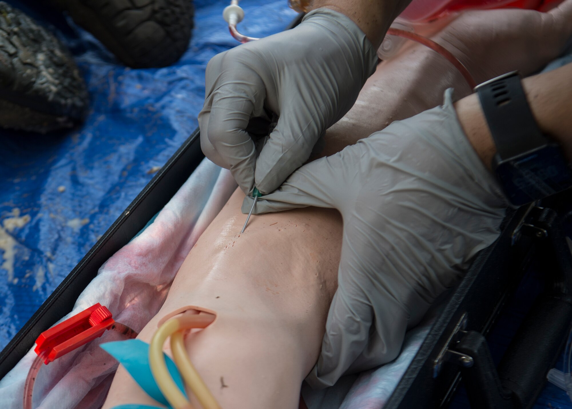 A medic inserts an IV into a training dummy during the U.S. Air Forces in Europe EMT Rodeo at Ramstein Air Base, Germany, July 23, 2019. Prosthetic limbs, makeup and imitation blood were used to make scenarios as real as possible. (U.S. Air Force photo by Staff Sgt. Kirby Turbak)