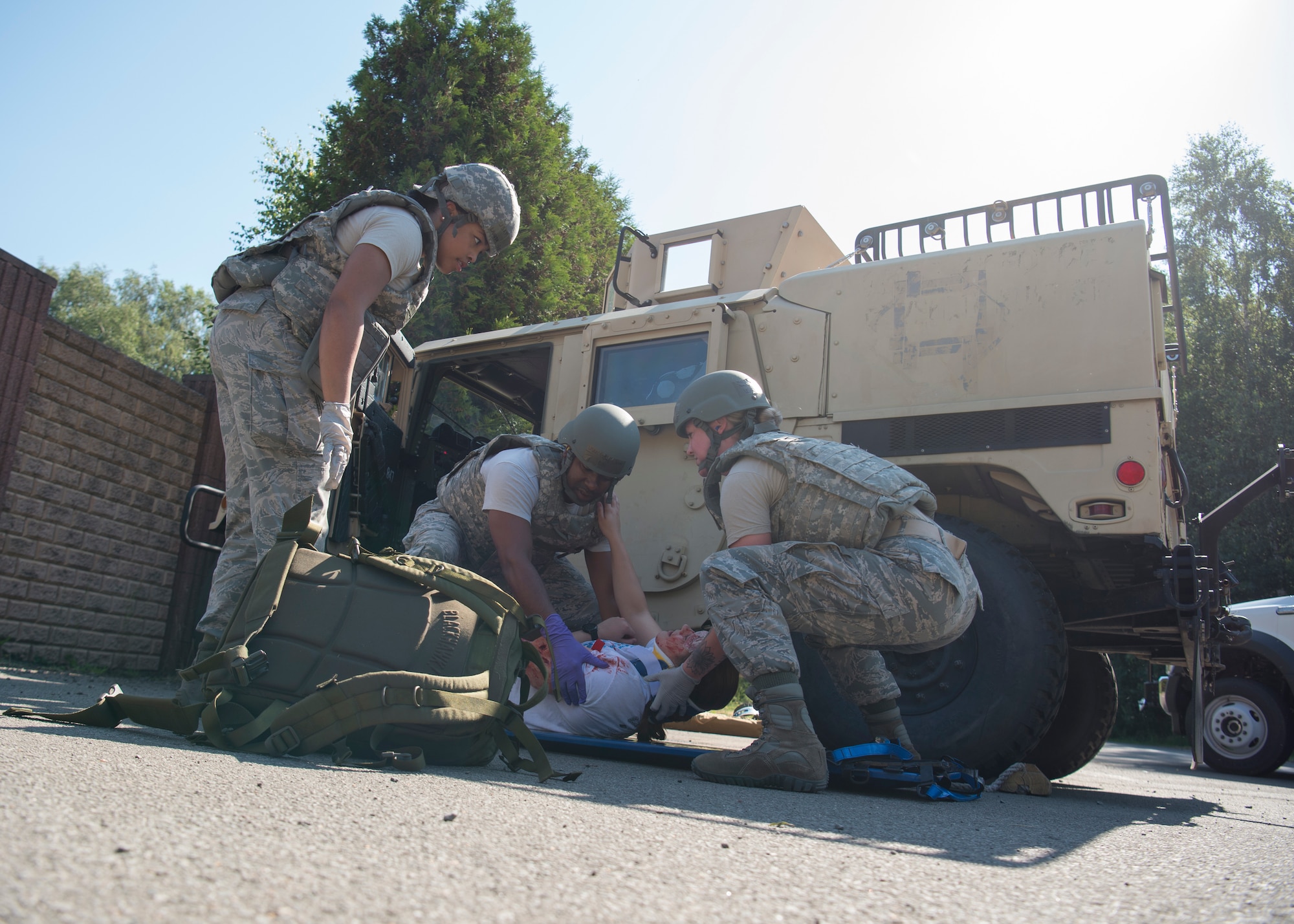 Medics retrieve a training victim during a vehicle extraction scenario at the U.S. Air Forces in Europe EMT Rodeo at Ramstein Air Base, Germany, July 24, 2019. To make this scenario more realistic, members of the 786th Civil Engineer Squadron Explosive Ordinance Disposal flight used controlled blasts to simulate being in a combat zone. (U.S. Air Force photo by Staff Sgt. Kirby Turbak)