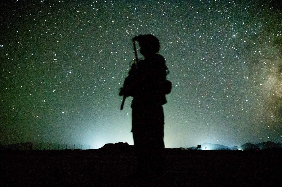 An airman stands below a starry sky.