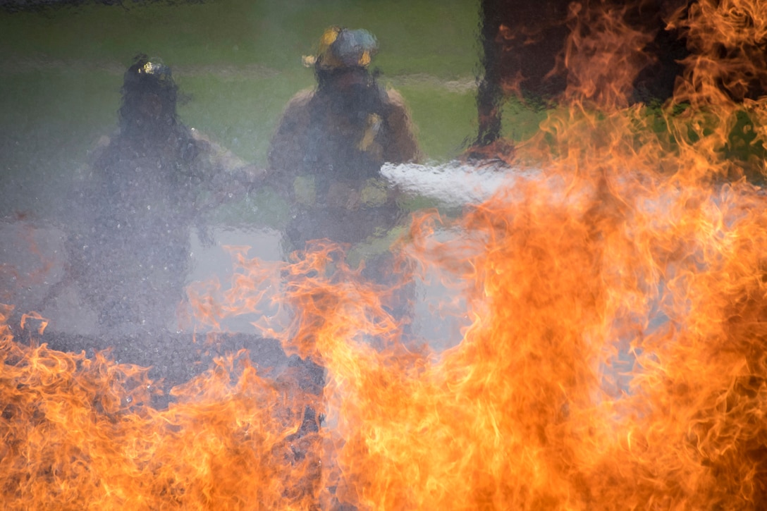 Two firefighters douse flames.