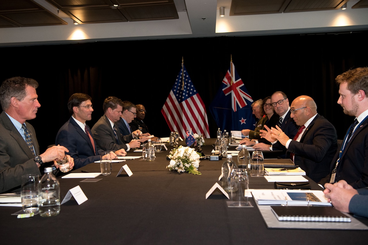 Two delegations sit on opposite sides of a table.