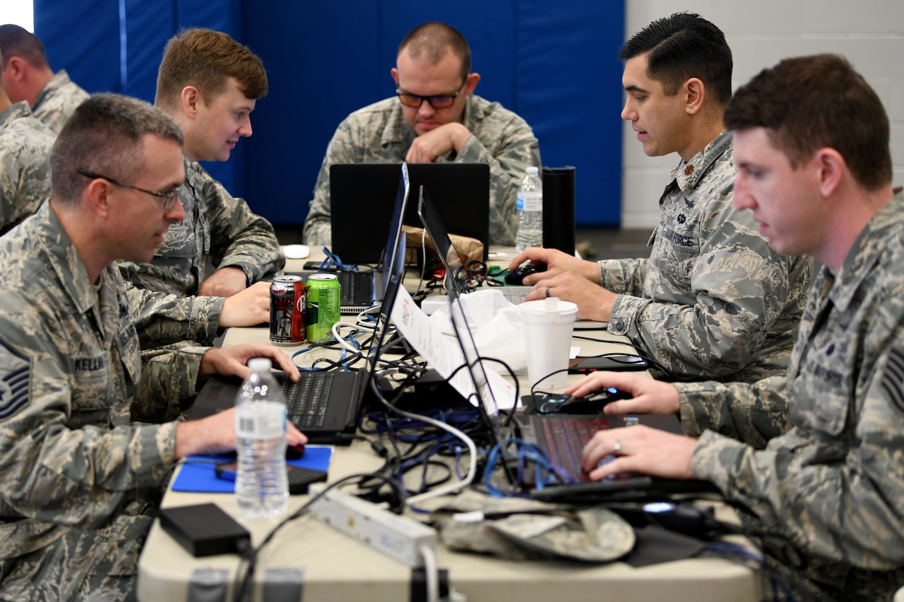 People work at a table work on laptops.