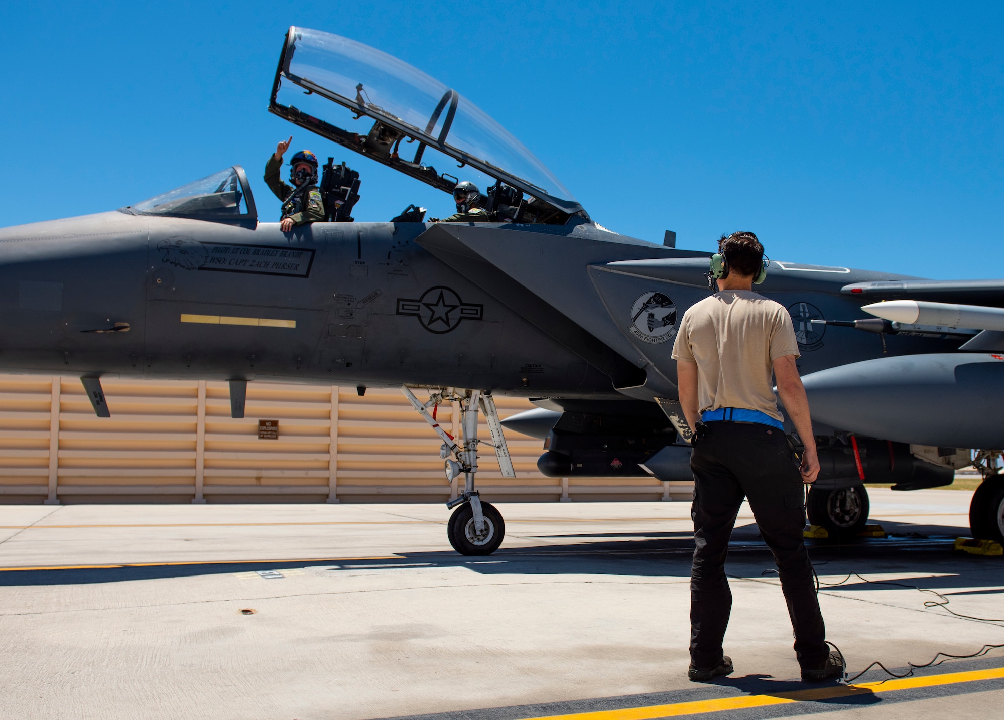 Pilot gives hand signal to Airman.