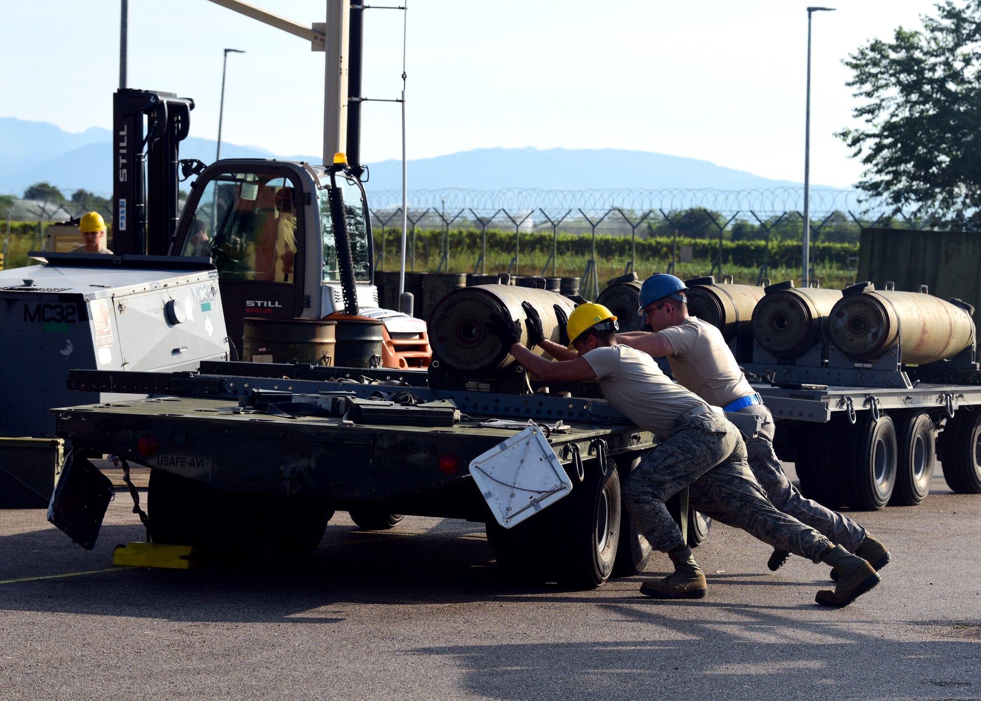 Airmen assist each other in loading munitions onto a trailer during Combat Ammunition Production Exercise 2019 on Aug. 7, 2019, at Aviano Air Base, Italy. Exercises such as CAPEX keep the Airmen of the munitions career field prepared and demonstrates USAFE’s ability to be rapidly ready for contingency operations. (U.S. Air Force photo by Airman 1st Class Caleb House)