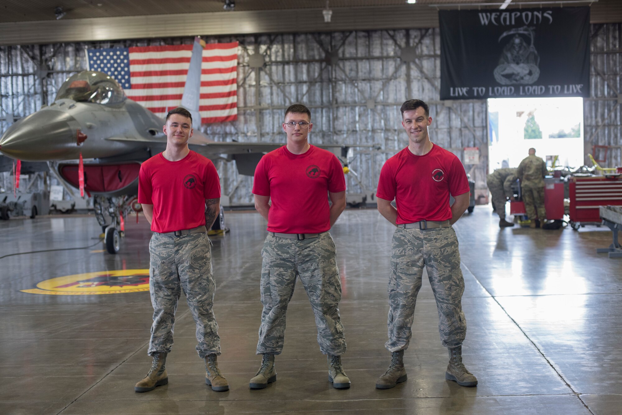 U.S. Air Force Airman 1st Class Adam Randles, left, and Senior Airman Cody Wilson, center, both 13th Aircraft Maintenance Unit load crew members, pose for a photo with Staff Sgt. Carlton Carpenter, right, a 13th AMU load crew chief, during the second quarter load crew competition at Misawa Air Base, Japan, Aug. 2, 2019. Wild Weasels from the 13th AMU and 14th AMU compete quarterly on their ability to quickly and properly arm F-16 Fighting Falcons with munitions. (U.S. Air Force photo by Takaharu Daibo)