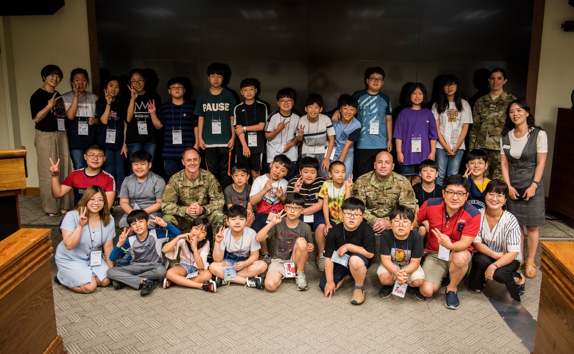 Korean children from the local area take a photo with 8th Fighter Wing leadership during a tour at Kunsan Air Base, Republic of Korea, Aug. 2, 2019. During their visit, the kids had a chance to get hands-on with some firefighting equipment and see one of the fire trucks use its water cannon. (U.S. Air Force photo by Senior Airman Stefan Alvarez)