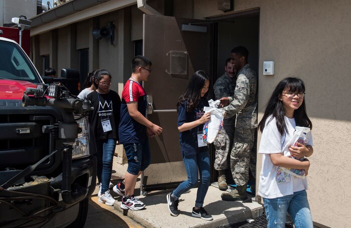 Airmen from the 8th Civil Engineer Squadron give gift bags to Korean children during a tour at Kunsan Air Base, Republic of Korea, Aug. 2, 2019. Their visit included a chance to get hands-on with some firefighting equipment and see one of the fire trucks use its water cannon. (U.S. Air Force photo by Senior Airman Stefan Alvarez)