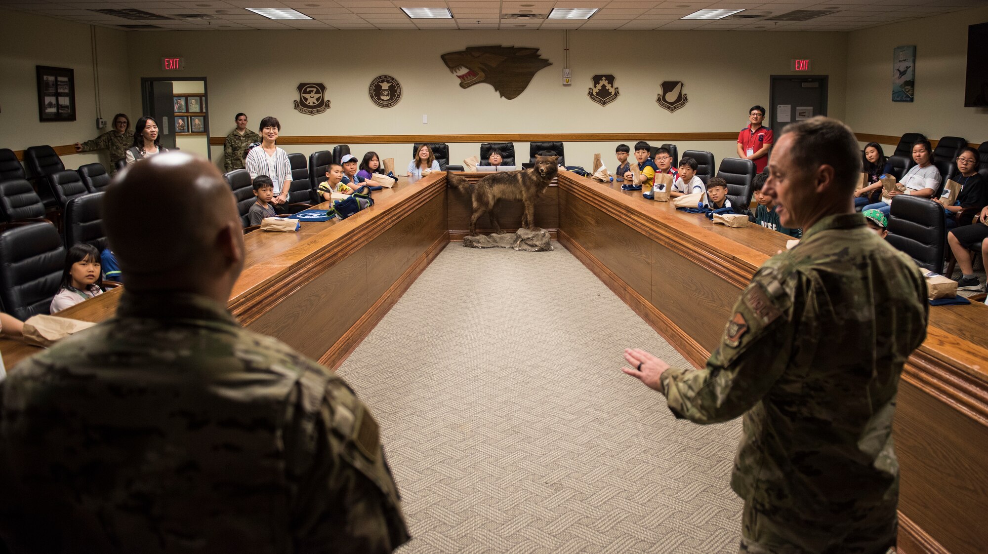 U.S. Air Force Col. Tad Clark (right), 8th Fighter Wing commander, and Chief Master Sgt. Steve Cenov (left), 8th FW command chief, speak to Korean children during a tour at Kunsan Air Base, Republic of Korea, Aug. 2, 2019. More than 20 children from the surrounding area were invited to tour the base and visit some of the facilities and organizations, such as the 8th Civil Engineer Squadron fire department. (U.S. Air Force photo by Senior Airman Stefan Alvarez)