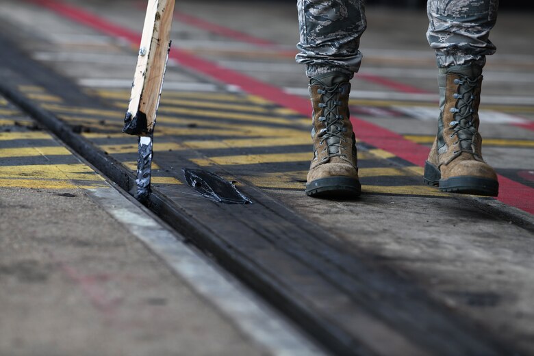 U.S. Air Force Senior Airman Matthew Bonjoe Rosario, 48th Civil Engineer Squadron structural apprentice, lathers grease on the door tracks of a protected aircraft shelter at Royal Air Force Lakenheath, England, Aug. 7, 2019. The monthly maintenance of the aircraft shelters ensures they are fully operational to store installation assets when needed. (U.S. Air Force photo by Airman 1st Class Shanice Williams-Jones)