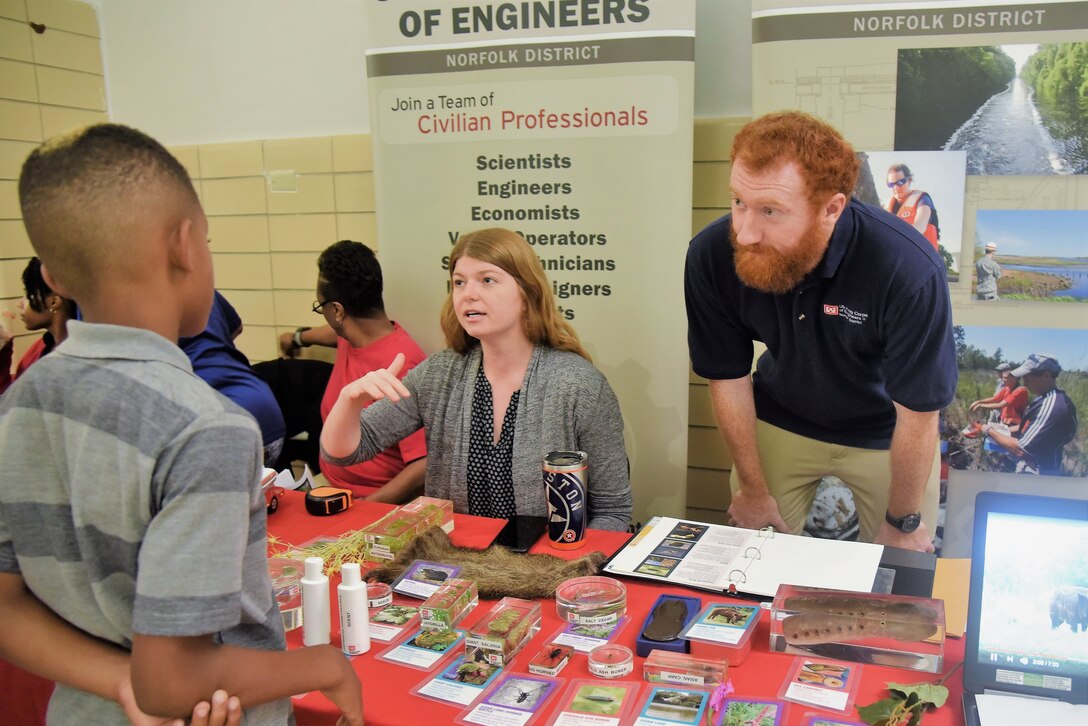 Norfolk District employees sit and stand at table while interacting with adults and children